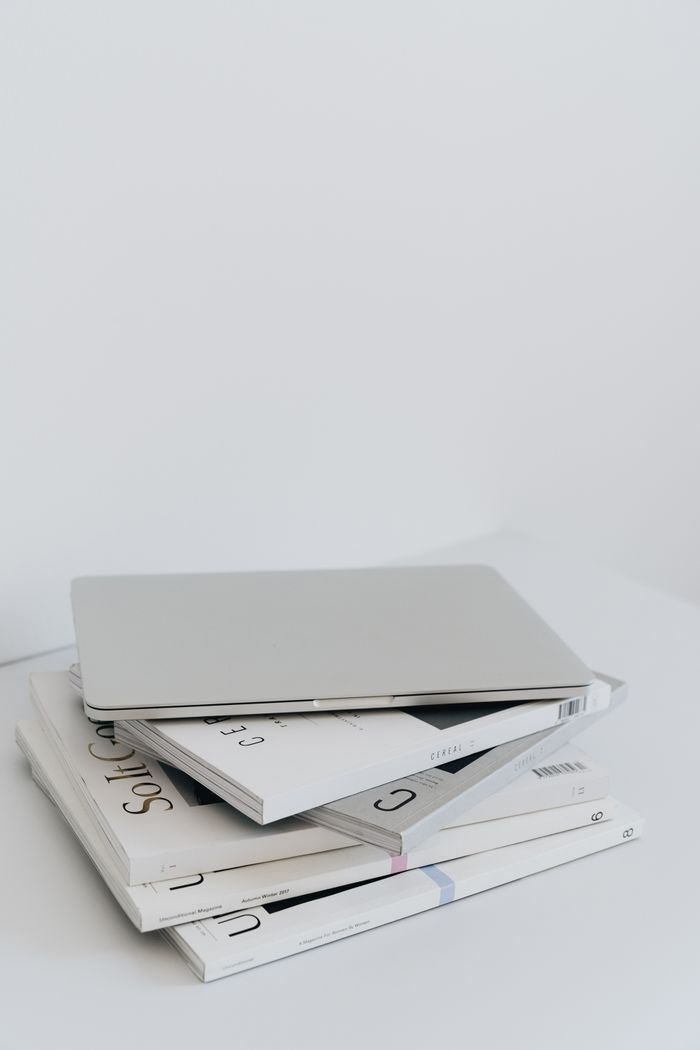 portfolio-01 Sleek laptop resting on a minimalist stack of books against a white background, offering ample copy space.